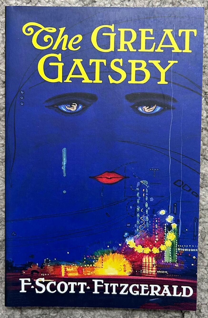The Great Gatsby by F. Scott Fitzgerald paperback book with blue illustrated cov